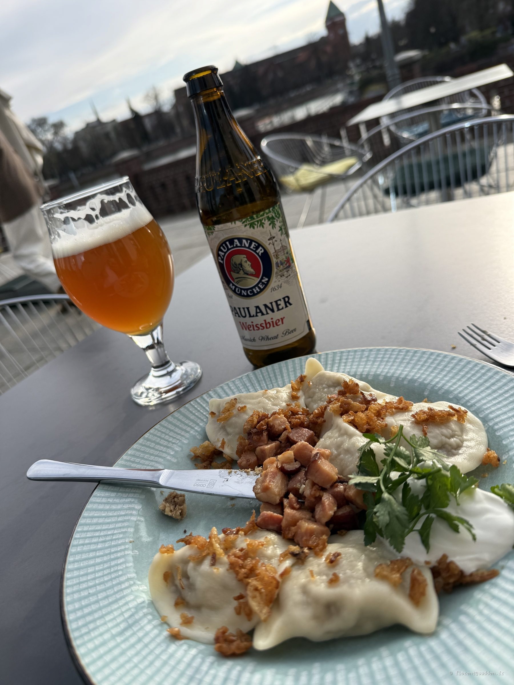 Assiette de pierogis aux lardons et bière blanche Paulaner sur une terrasse à Wrocław