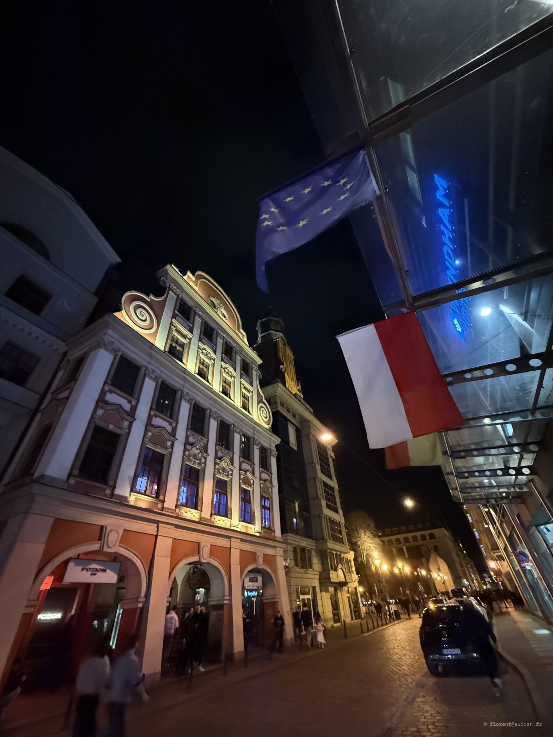 Drapeaux européen et polonais devant un hôtel de Wrocław la nuit