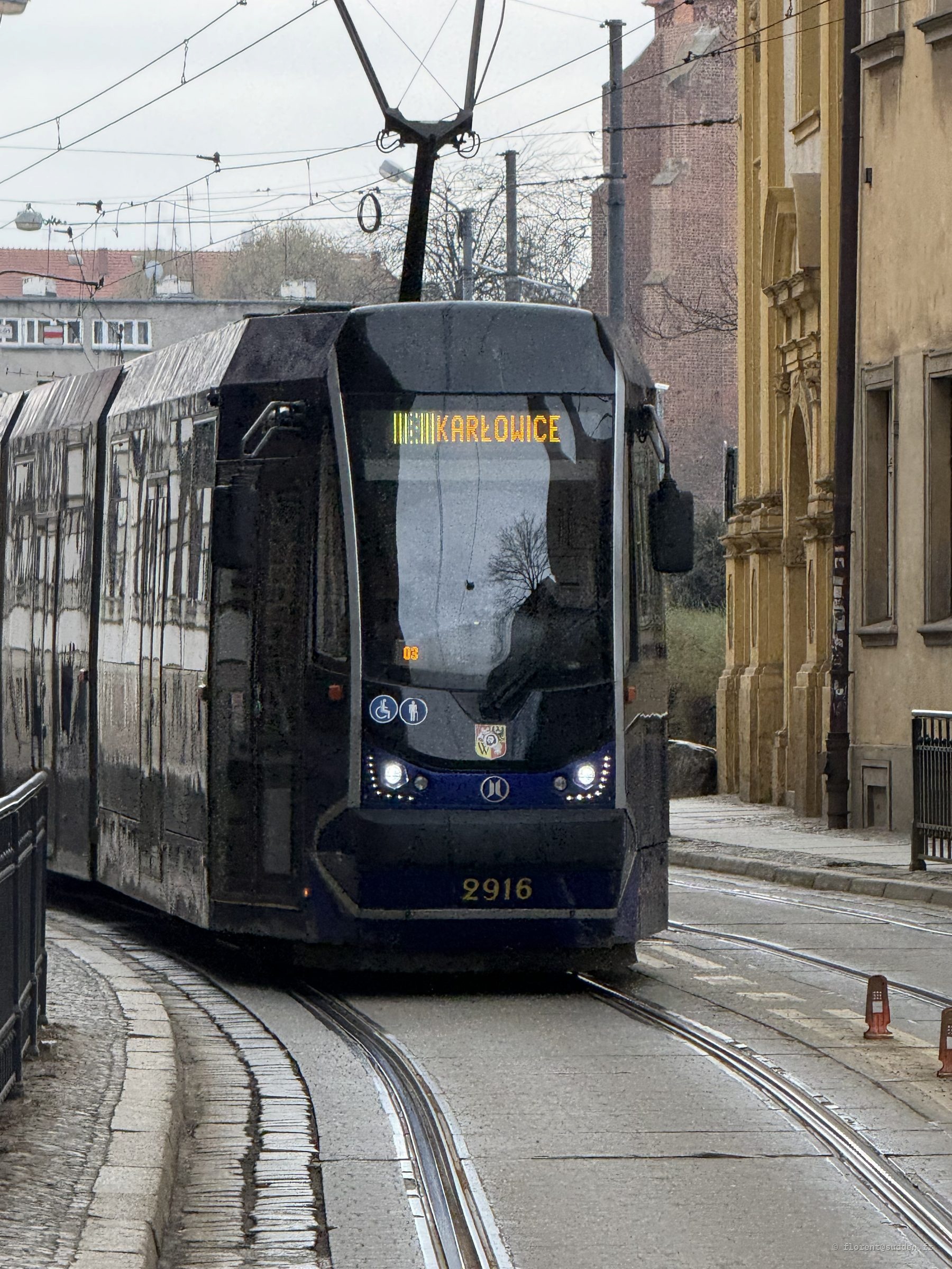 Tramway moderne bleu marine et jaune en direction de Karłowice dans une rue de Wrocław